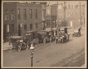 Ansicht einer unbekannten Straße mit mehreren Autos und einem Pferdewagen der St. Louis Bakery Company am Straßenrand